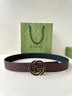 Brown leather belt with circular GG buckle, stitched strap, visible holes
