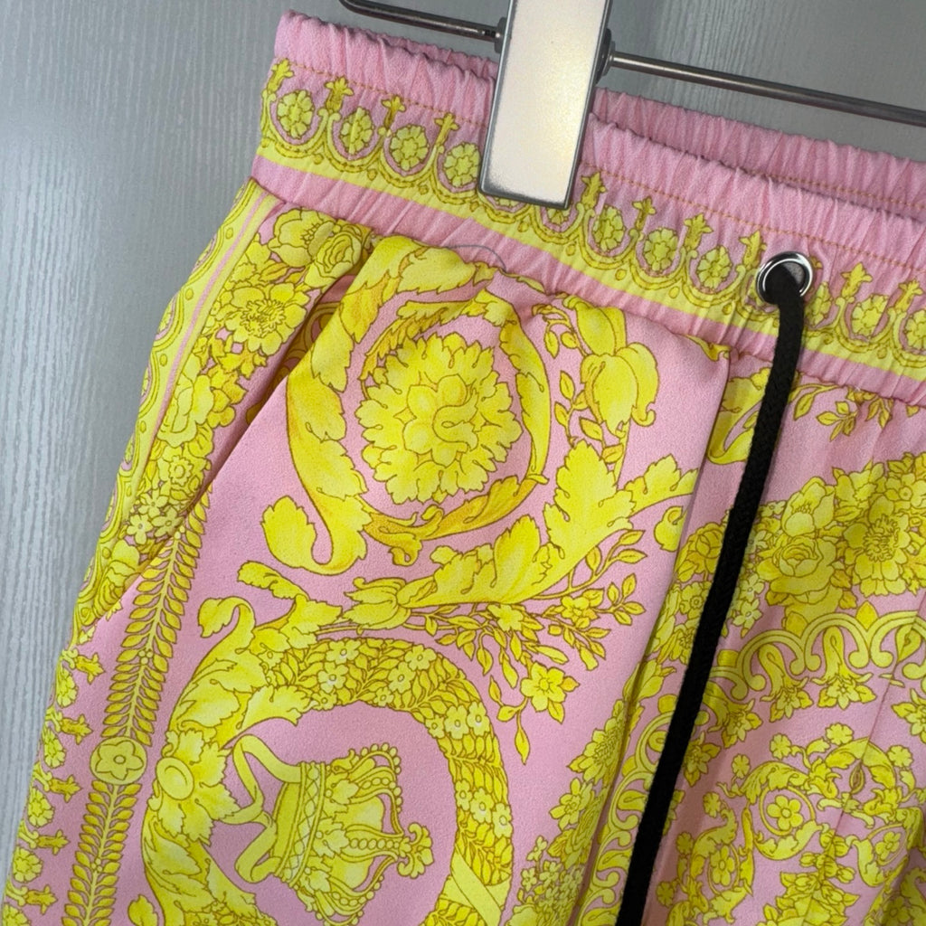 Versace shorts close-up showing pink elastic waistband with yellow ornate pattern.