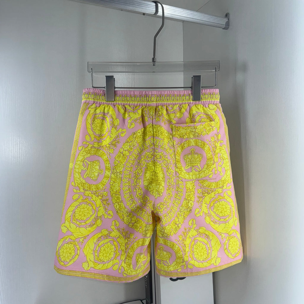 Versace shorts with yellow-and-pink ornate pattern, elastic waist and black drawstring.