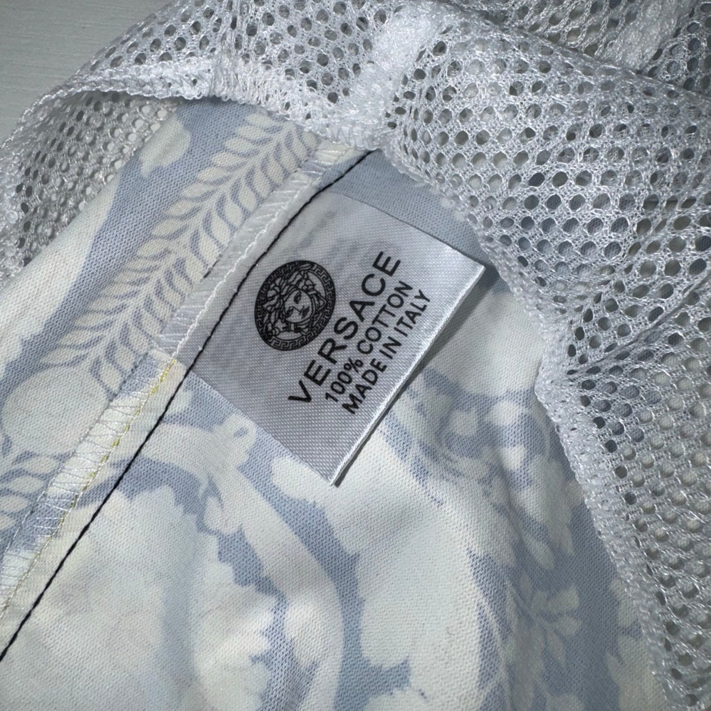 White mesh lining panel with care label reading “VERSACE 100% COTTON MADE IN ITALY”