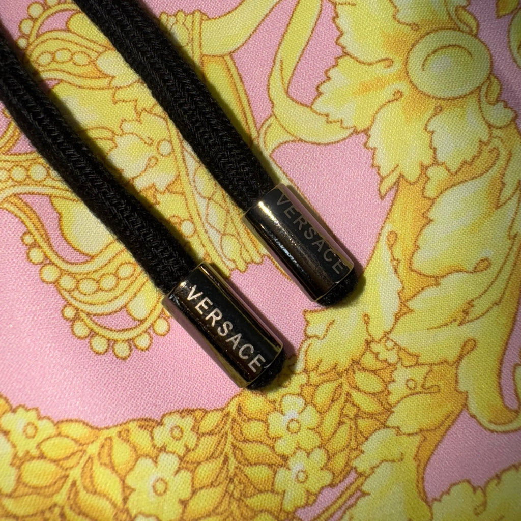 Versace shorts drawstrings and waistband label on yellow and pink baroque fabric.