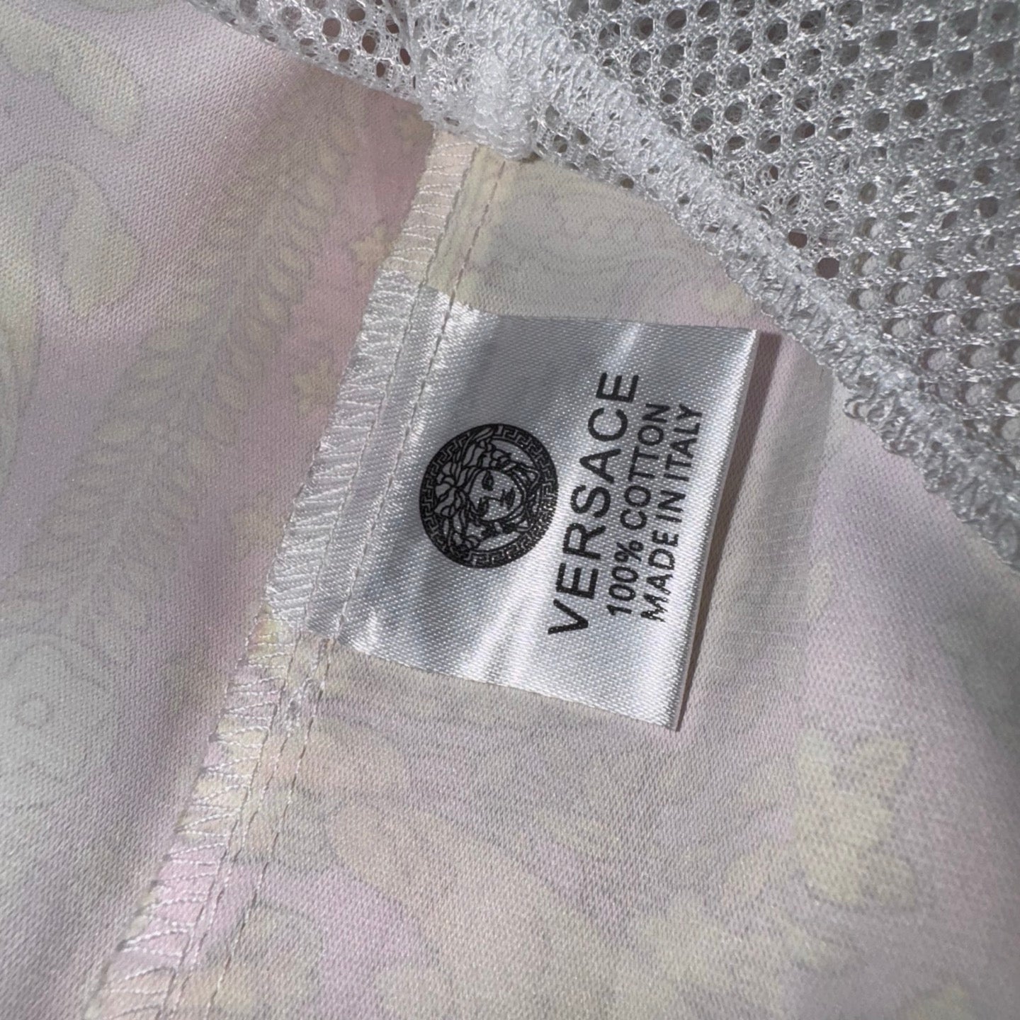 Versace white shorts inner care label with printed brand and made information.