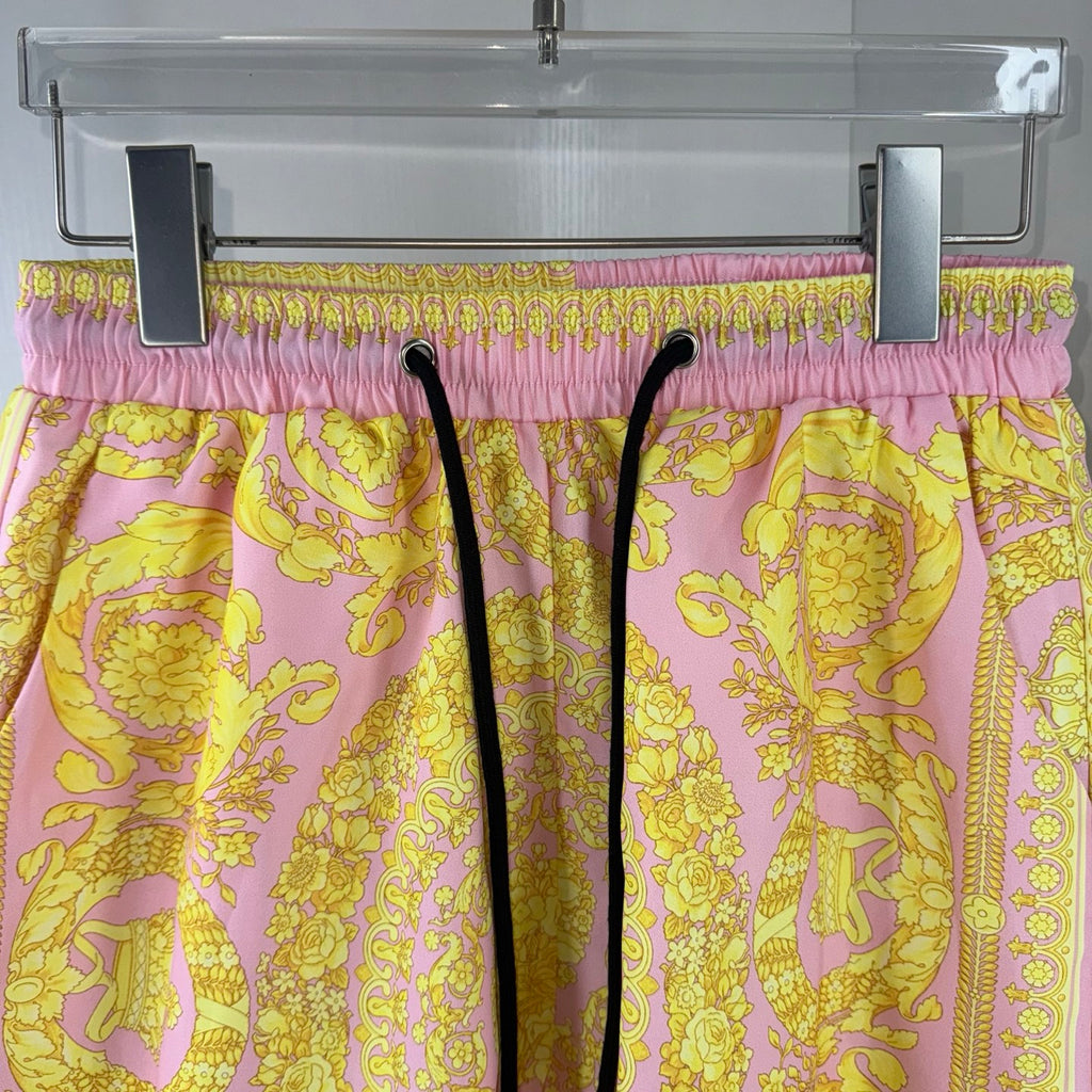 Versace shorts on hanger with purple-pink elastic waistband and yellow baroque print.