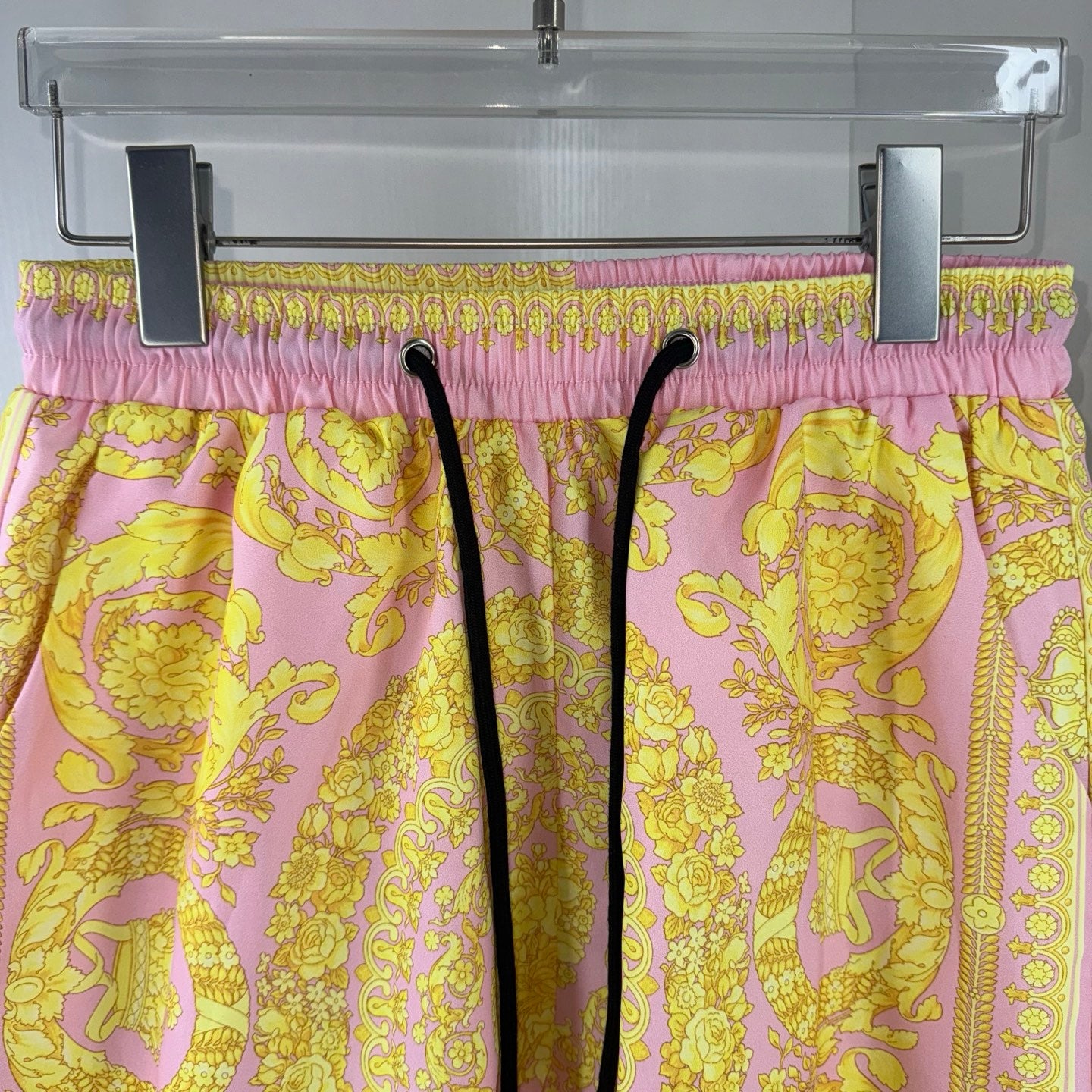 Versace shorts on hanger with purple-pink elastic waistband and yellow baroque print.