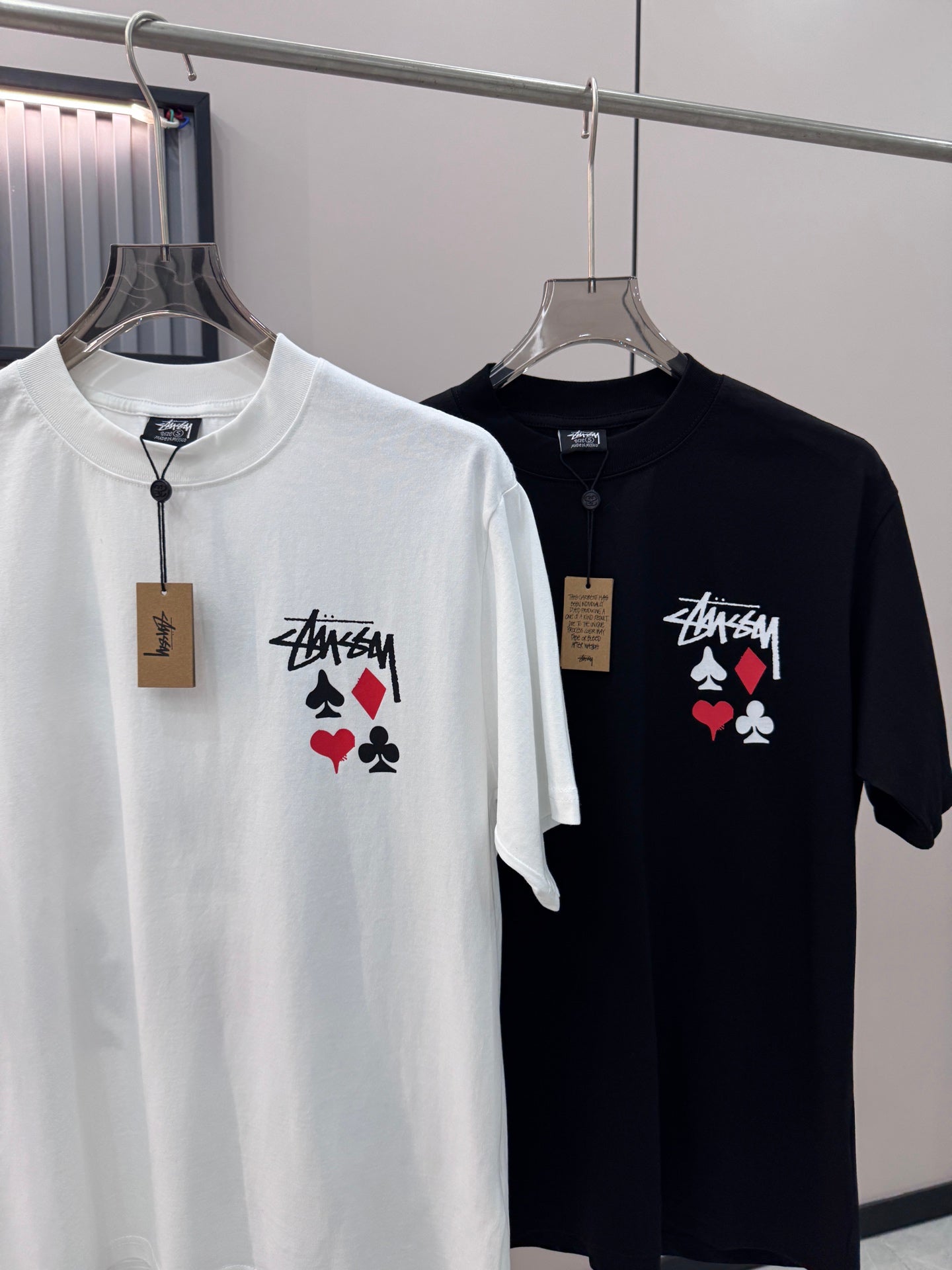 White and black short-sleeve T-shirts with playing-card graphic on hangers