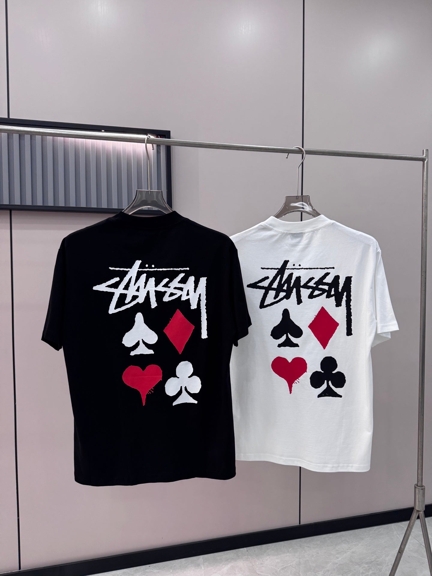 Black and white short-sleeve T-shirts with playing-card graphic on hangers