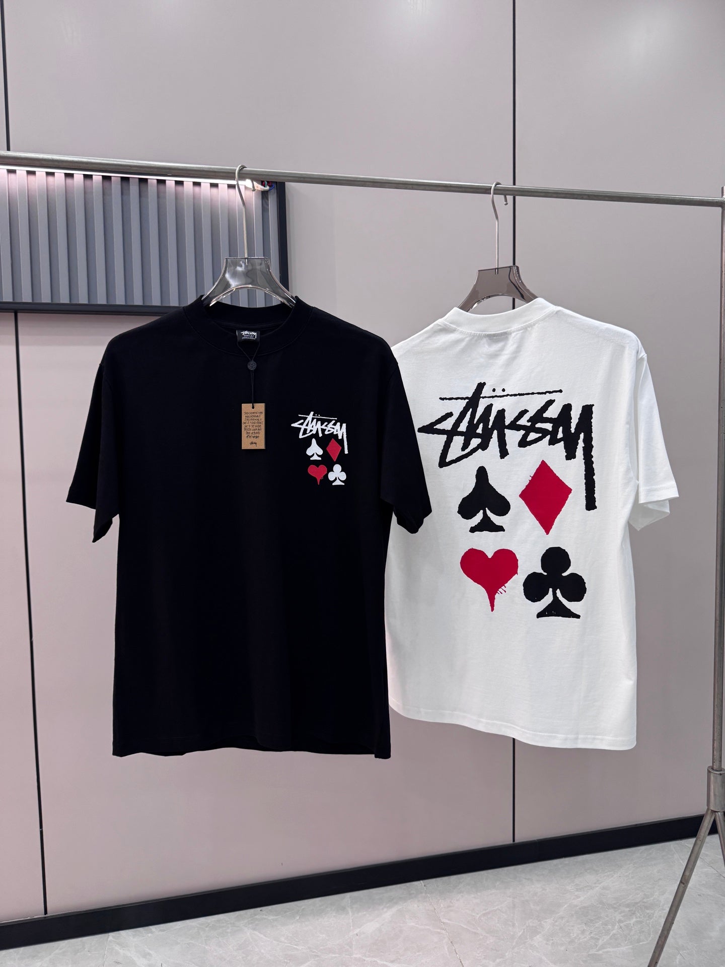 Black short-sleeve T-shirt with chest graphic of playing cards on hanger