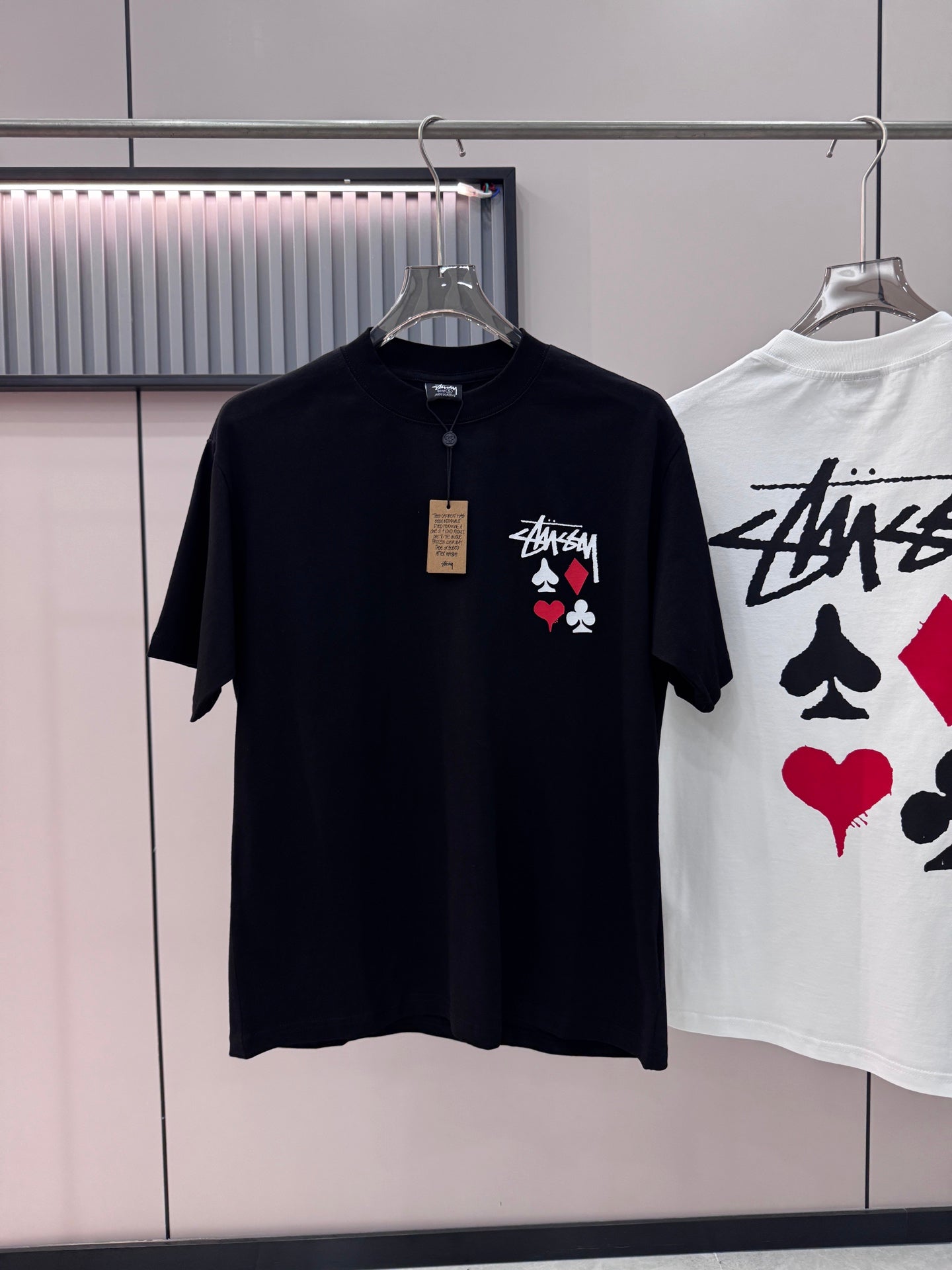 Black short-sleeve T-shirt with playing-card graphic on chest, on hanger