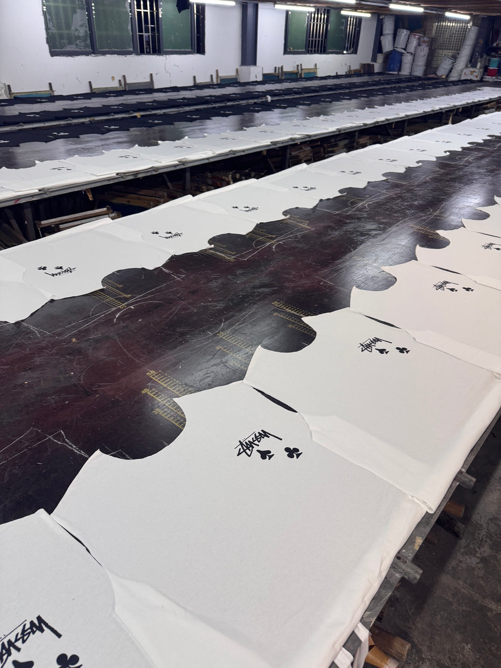 White T-shirts on a screen-printing table with black ink designs