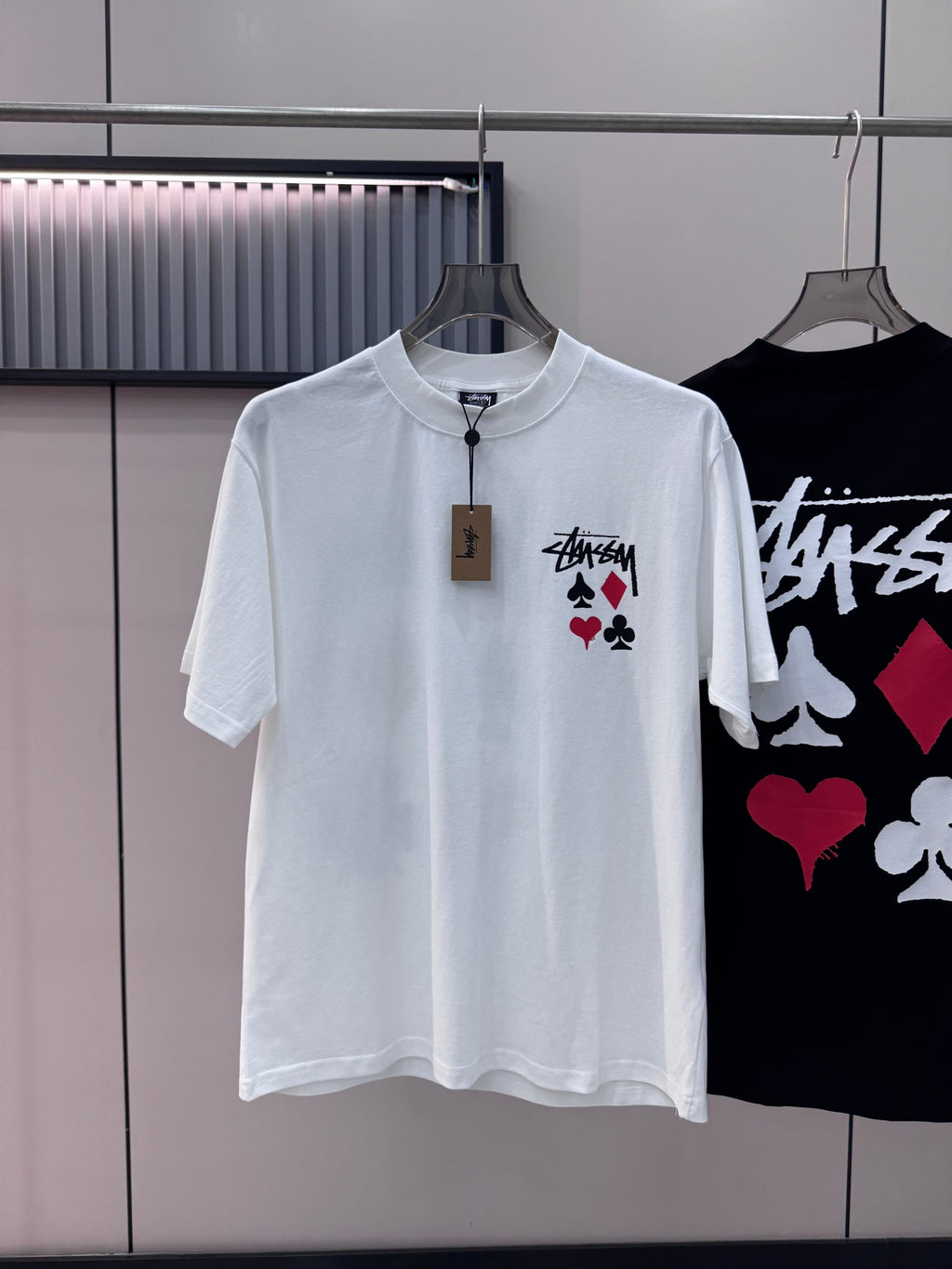 White short-sleeve T-shirt with Stussy graphic and playing-card symbols on chest