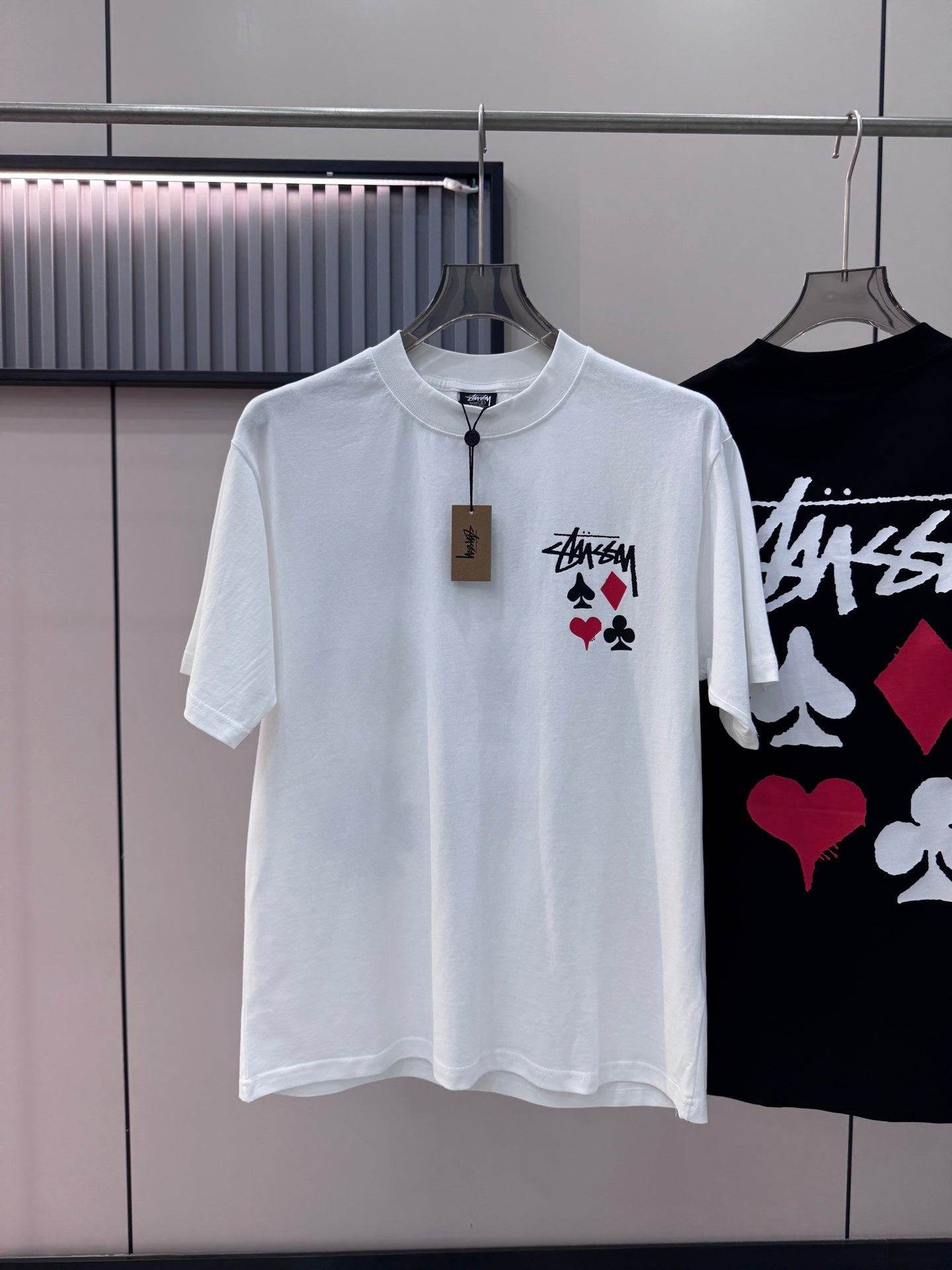White short-sleeve T-shirt with Stussy graphic and playing-card symbols on chest