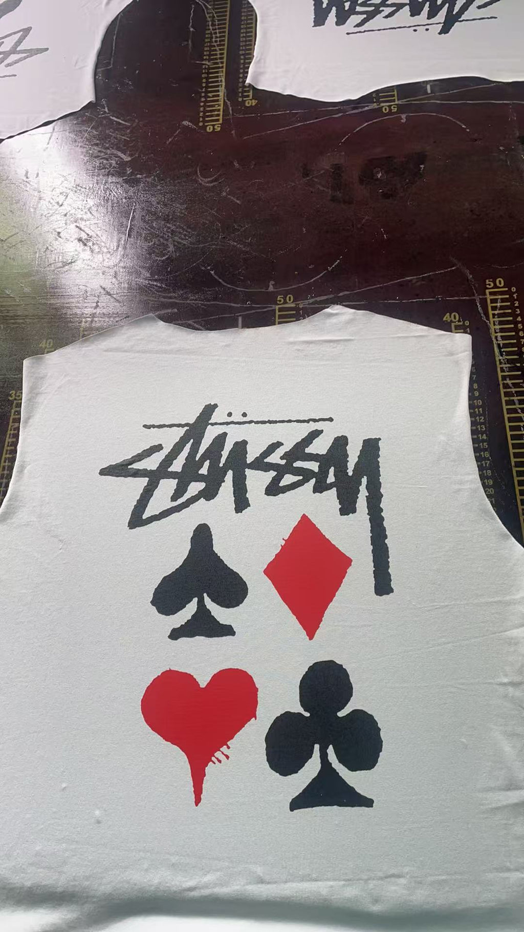 White graphic T-shirt with Stussy-style script and red/black playing card icons