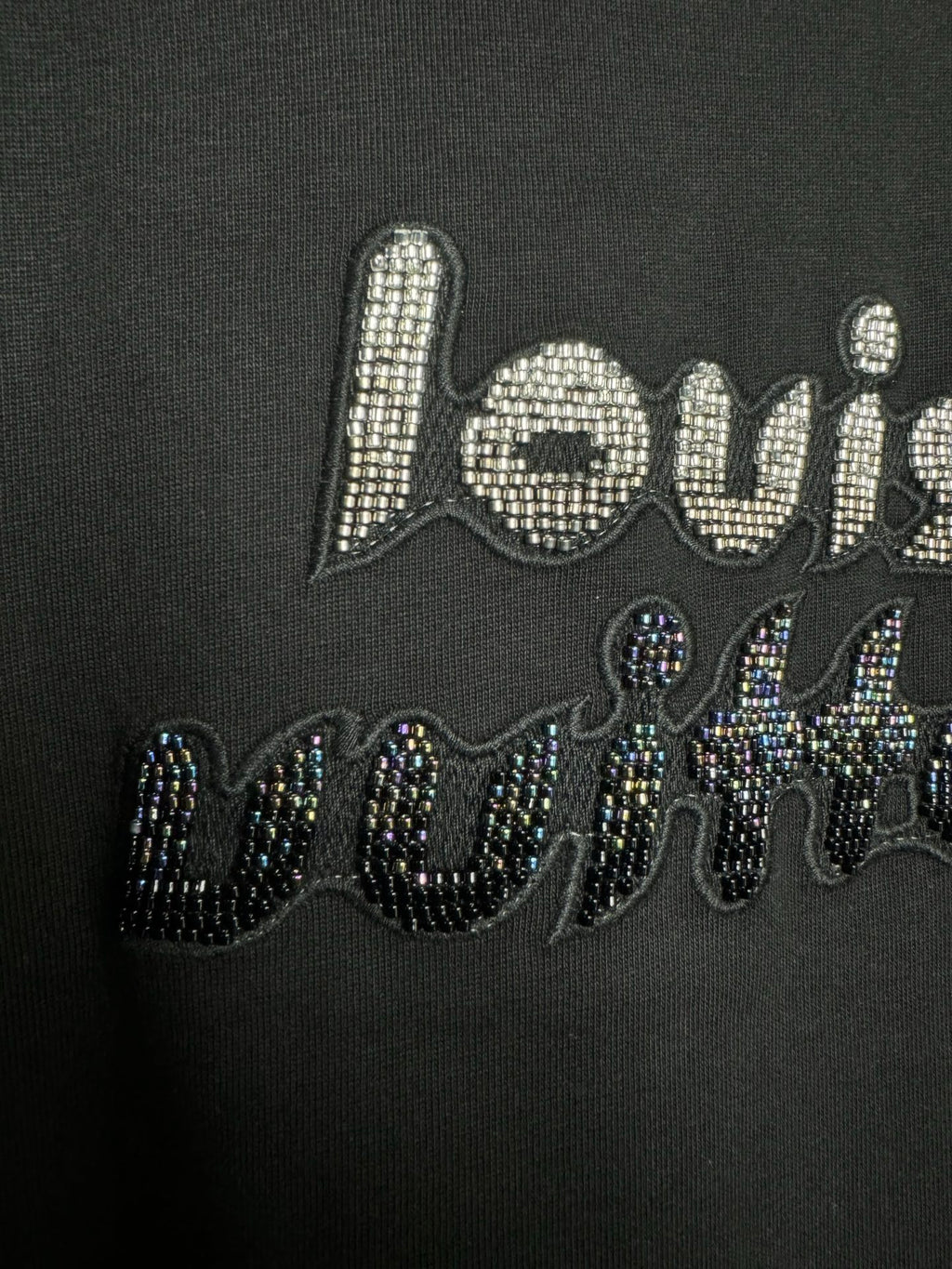 Close-up of black T-shirt chest graphic with rhinestone "louis" text