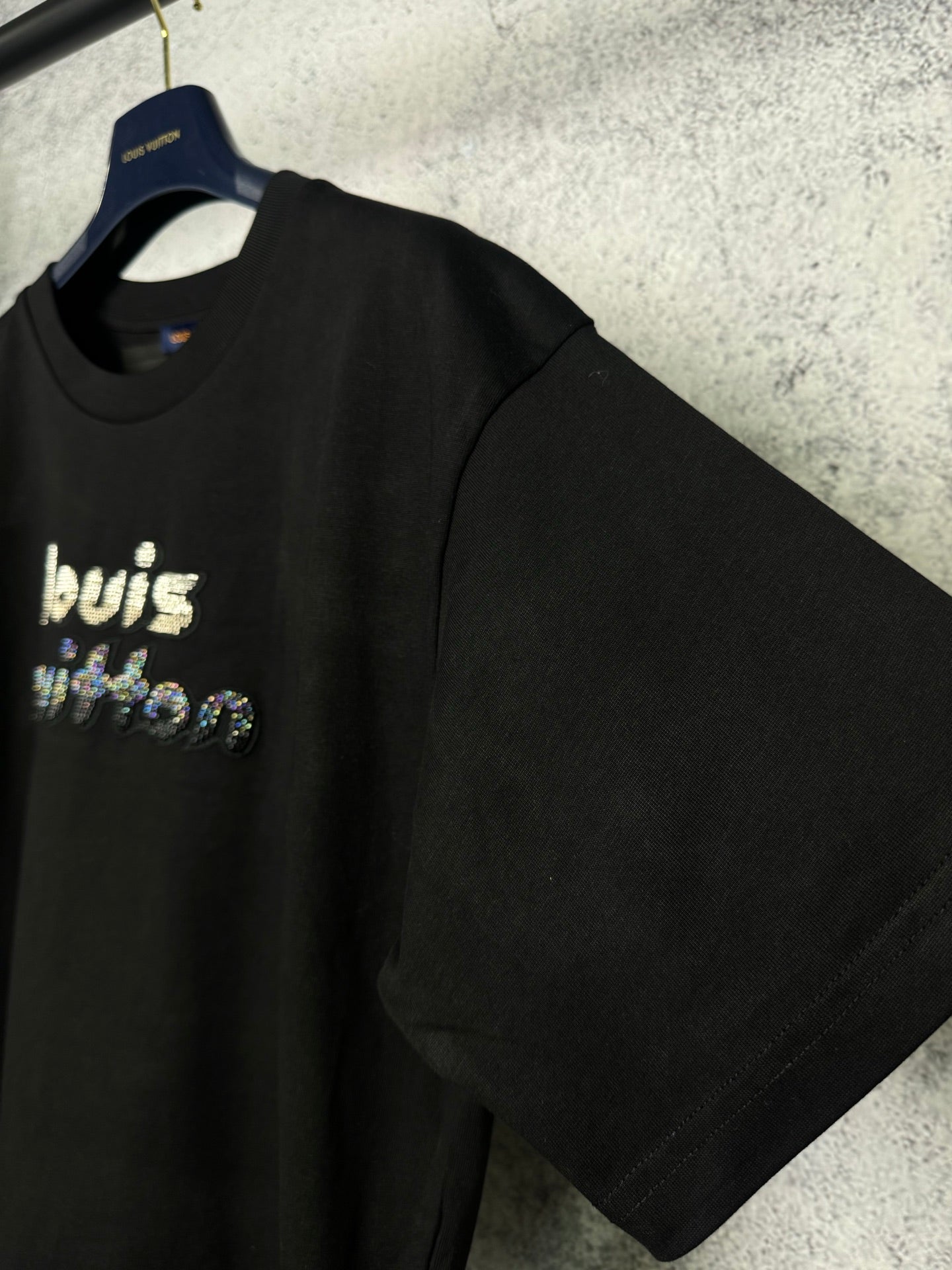 Black short-sleeve T-shirt on a hanger with rhinestone "louis" front graphic