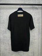 Black short-sleeve T-shirt back view with yellow brand label at the upper back
