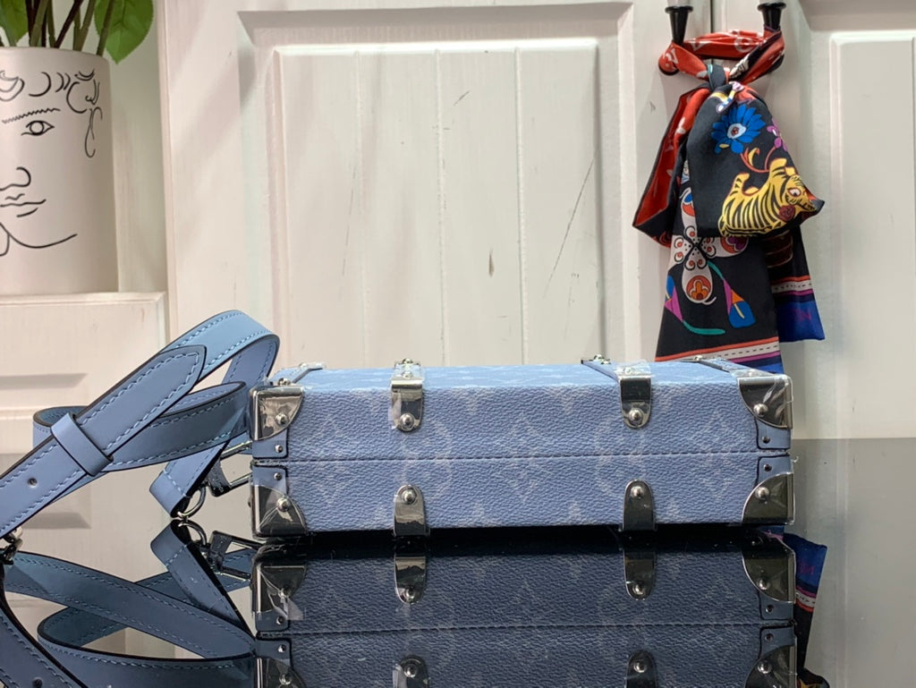 Light blue Louis Vuitton trunk bag with top handle, front lock, and stud details