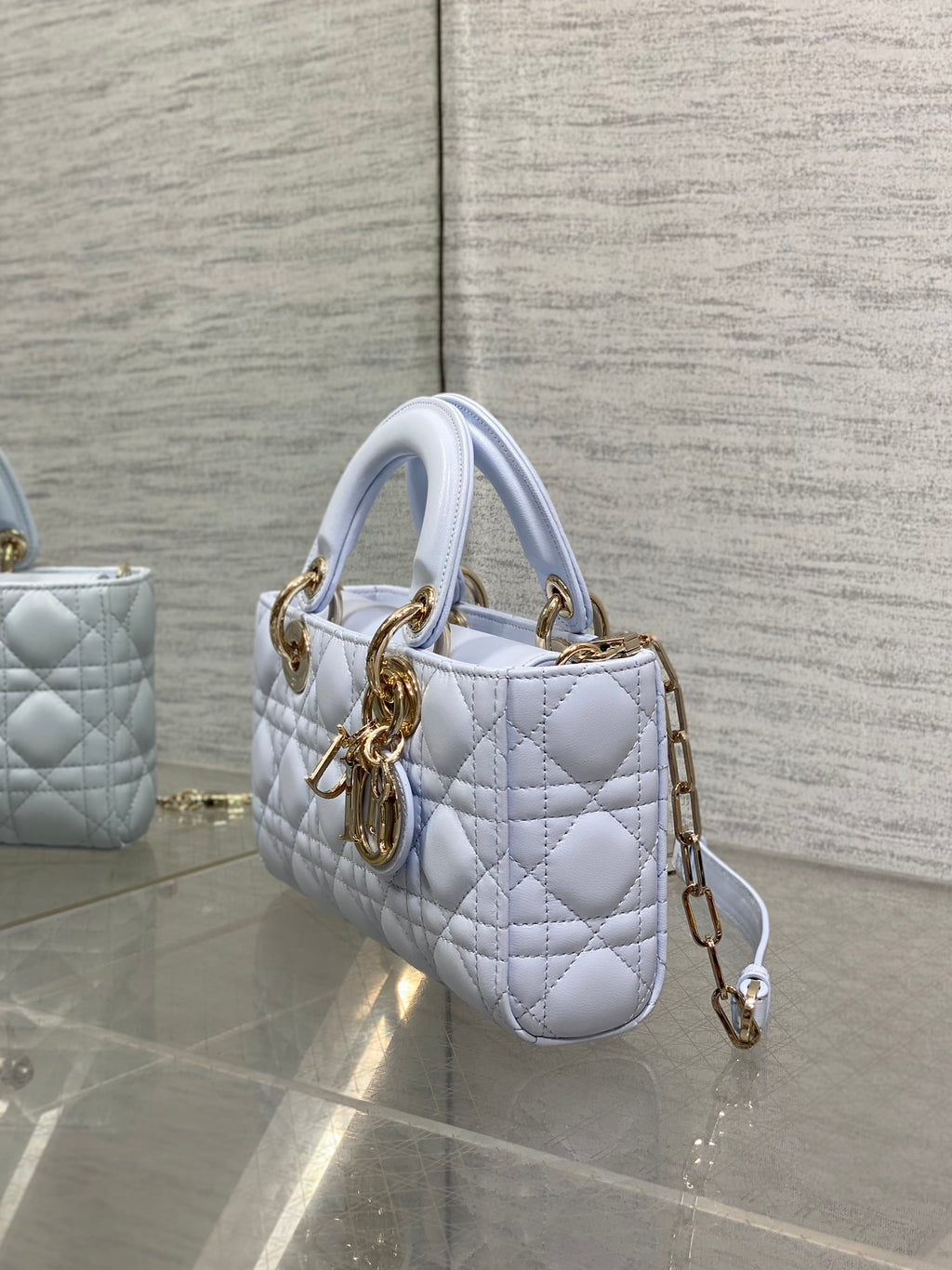 Light blue quilted mini handbag with top handles and gold-tone chain strap