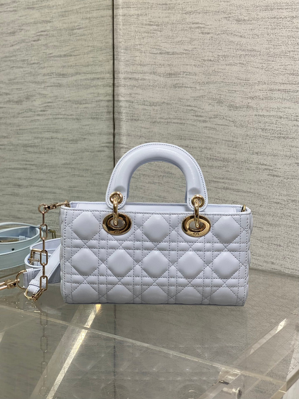 Light blue quilted handbag with top handles and gold-tone rings, with shoulder strap