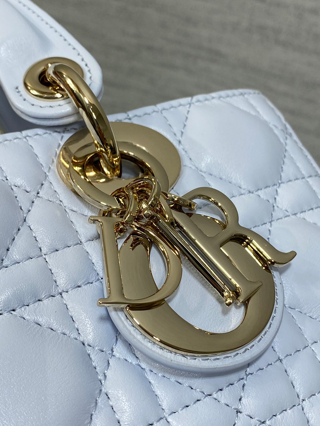 Gold-tone logo charm and clasp on quilted light blue handbag hardware