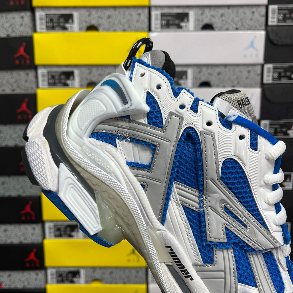 Front three-quarter view of white and blue lace-up Balenciaga runner sneakers