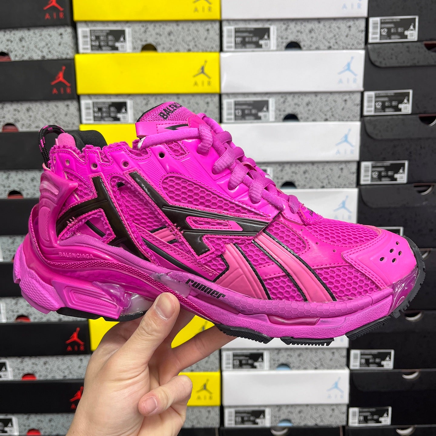 Pink athletic sneaker with black side stripes, perforated panels, and lace-up closure