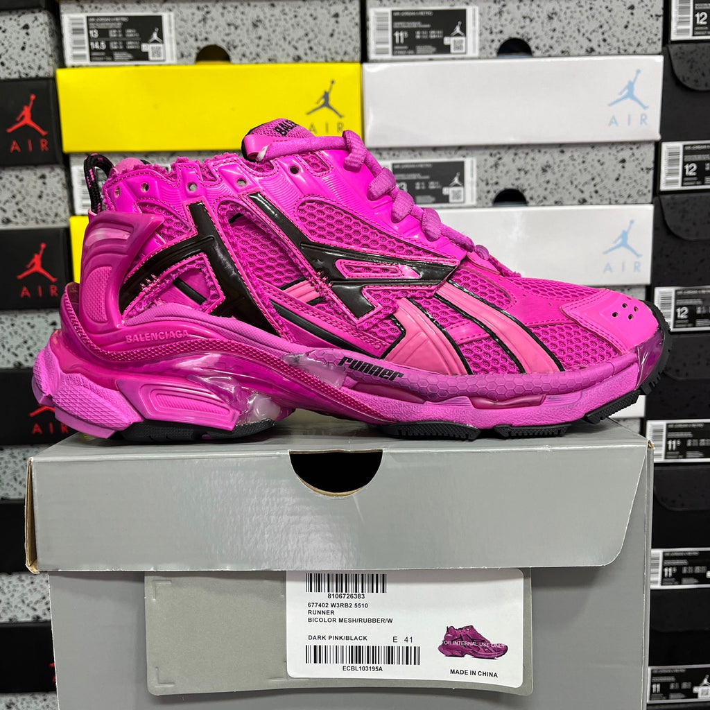 Pink lace-up sneaker with black accents and chunky sole, shown on a retail box