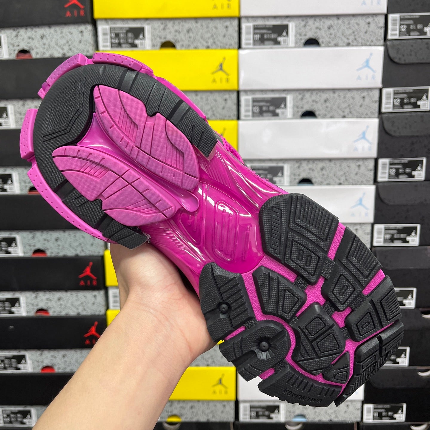 Pink and black outsole of a sneaker with tread pattern and rubber traction blocks