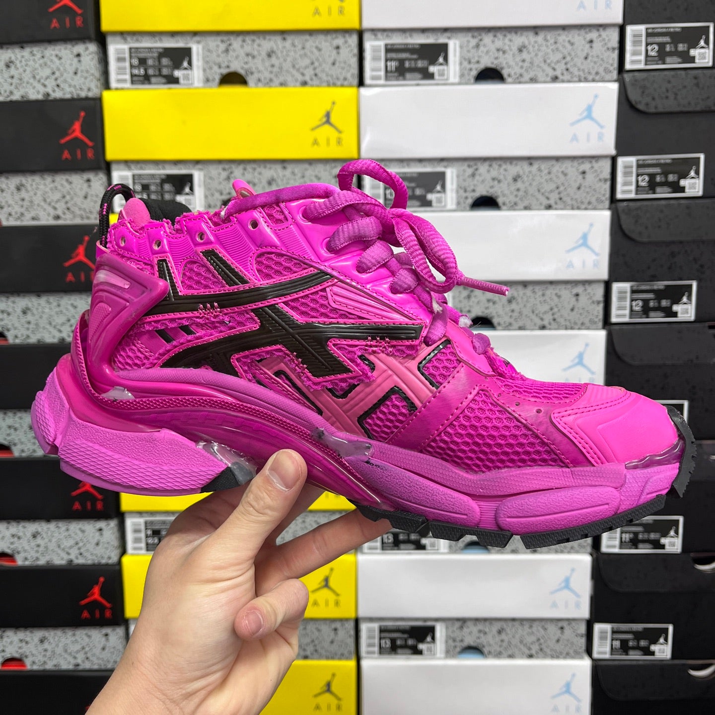 Pink lace-up athletic sneaker with black side stripes, perforations, and thick sole