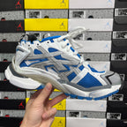 Low-angle view of white and blue lace-up chunky sneakers with textured sole