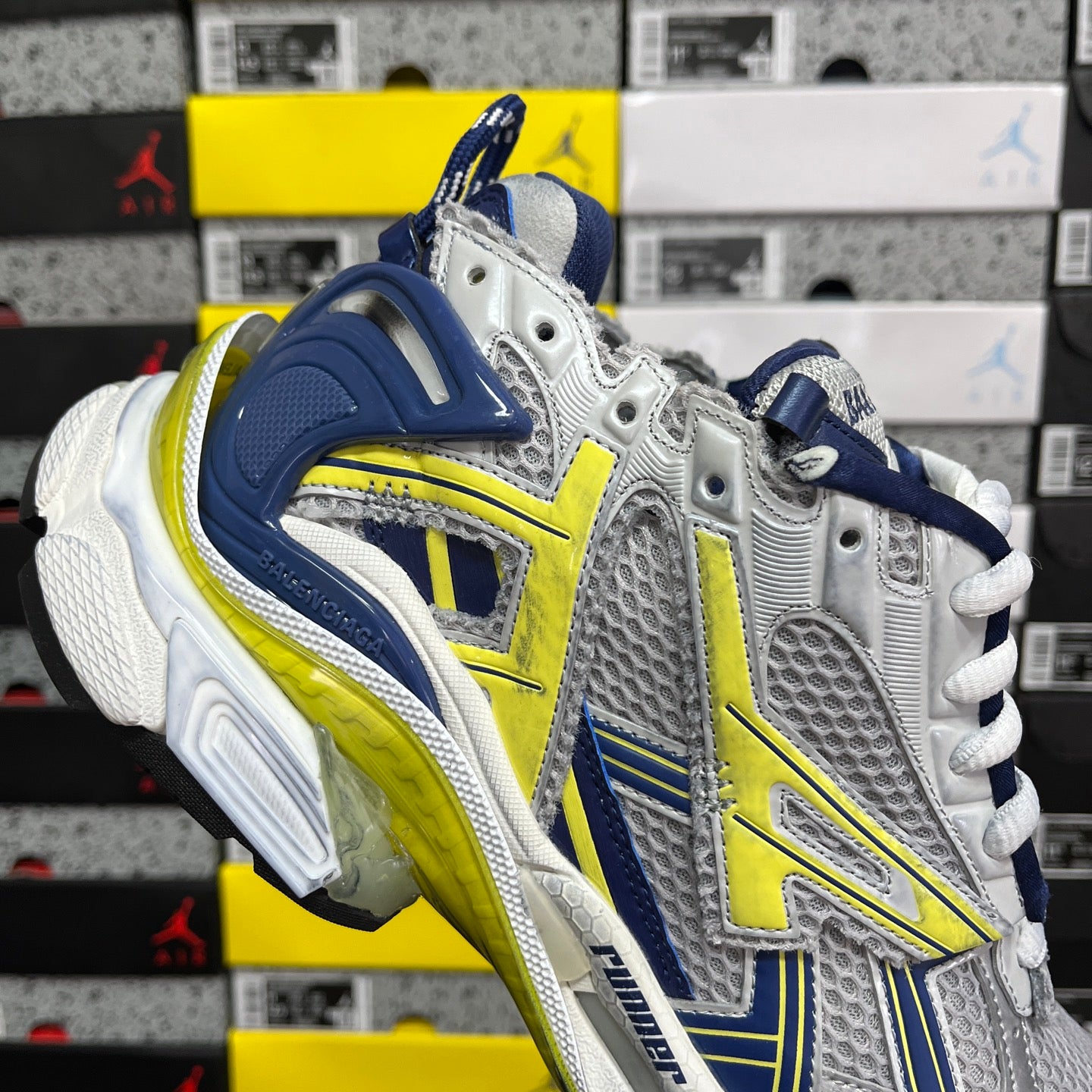 Unisex runner shoes angled side view, silver upper with navy heel and yellow-green trim