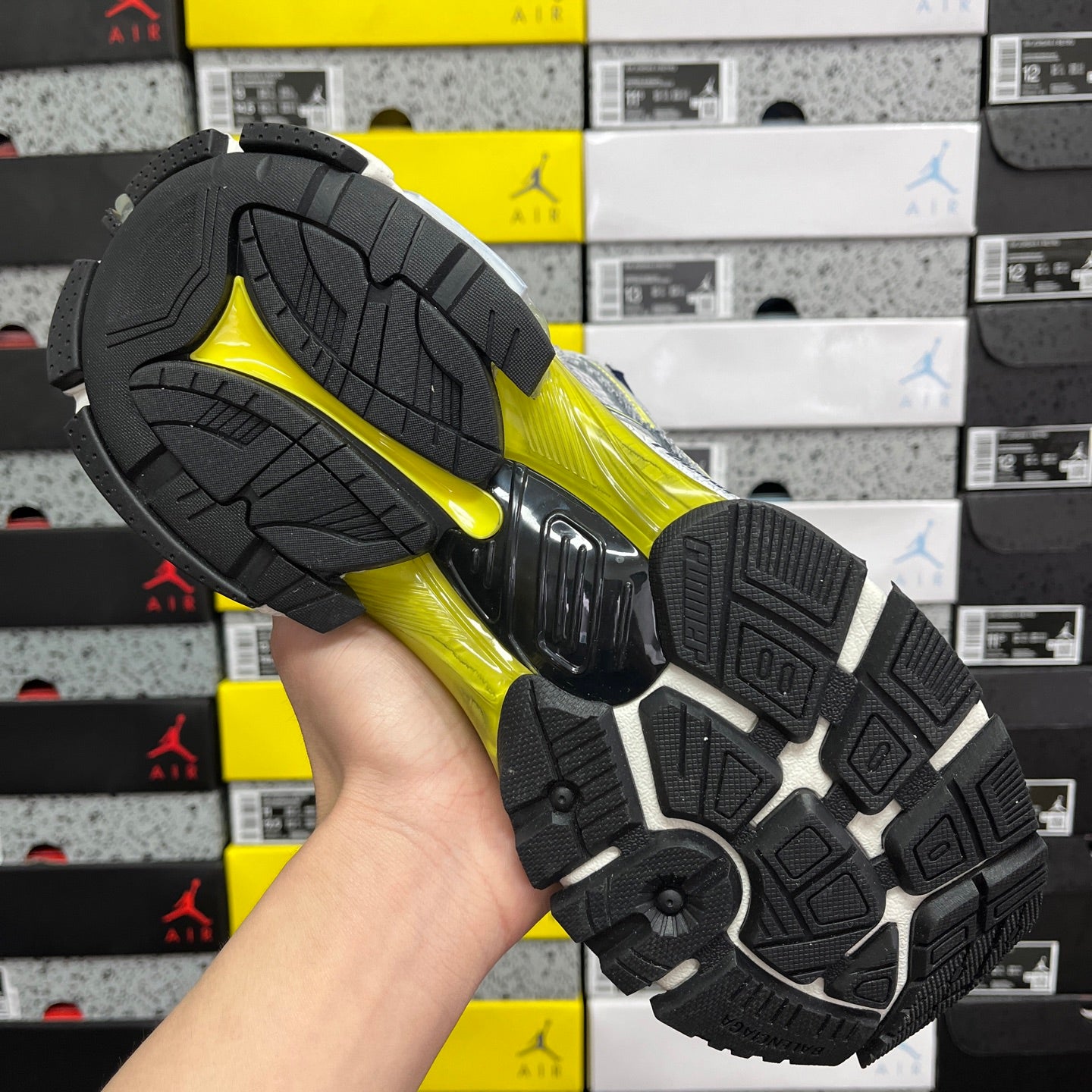 Unisex runner shoe outsole, black tread with yellow-green and silver details