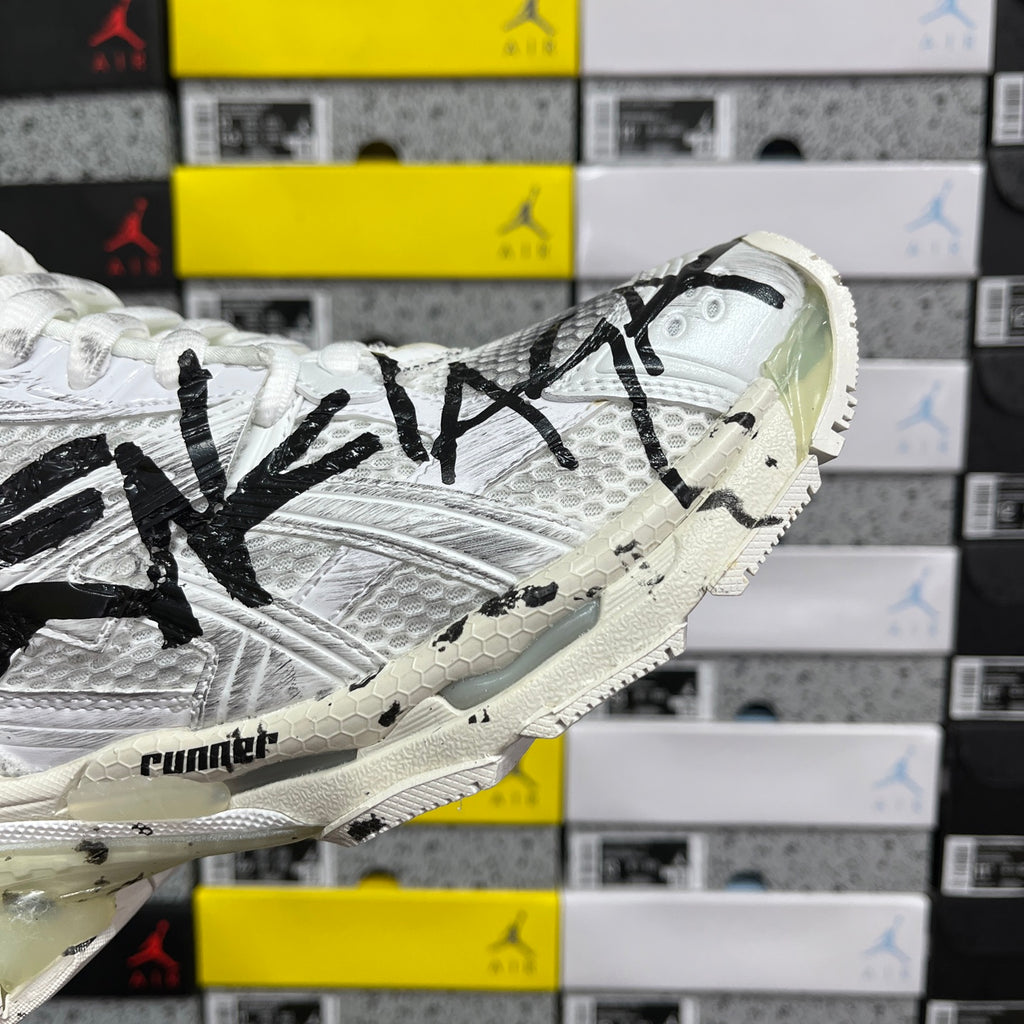 White Balenciaga sneakers with black writing across side and chunky outsole tread