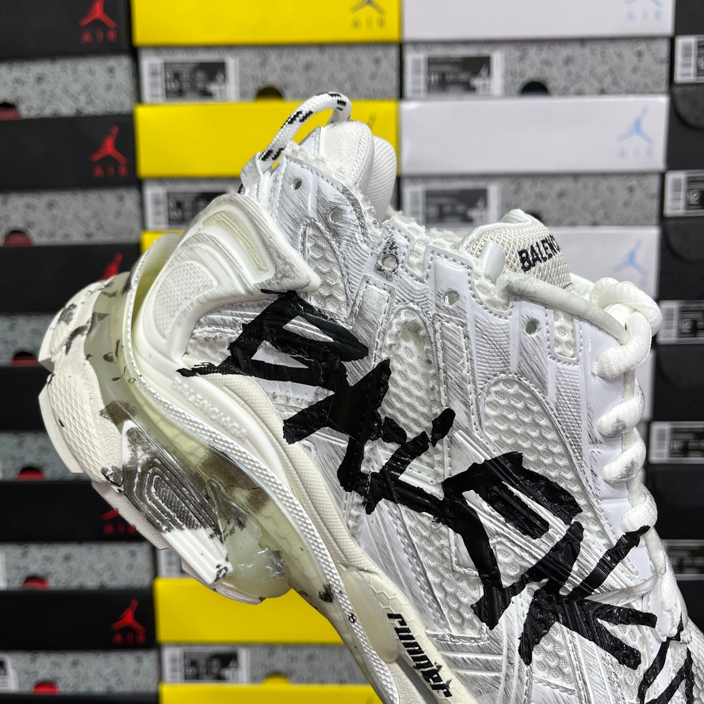 White Balenciaga sneakers with black graffiti logo and thick cushioned midsole