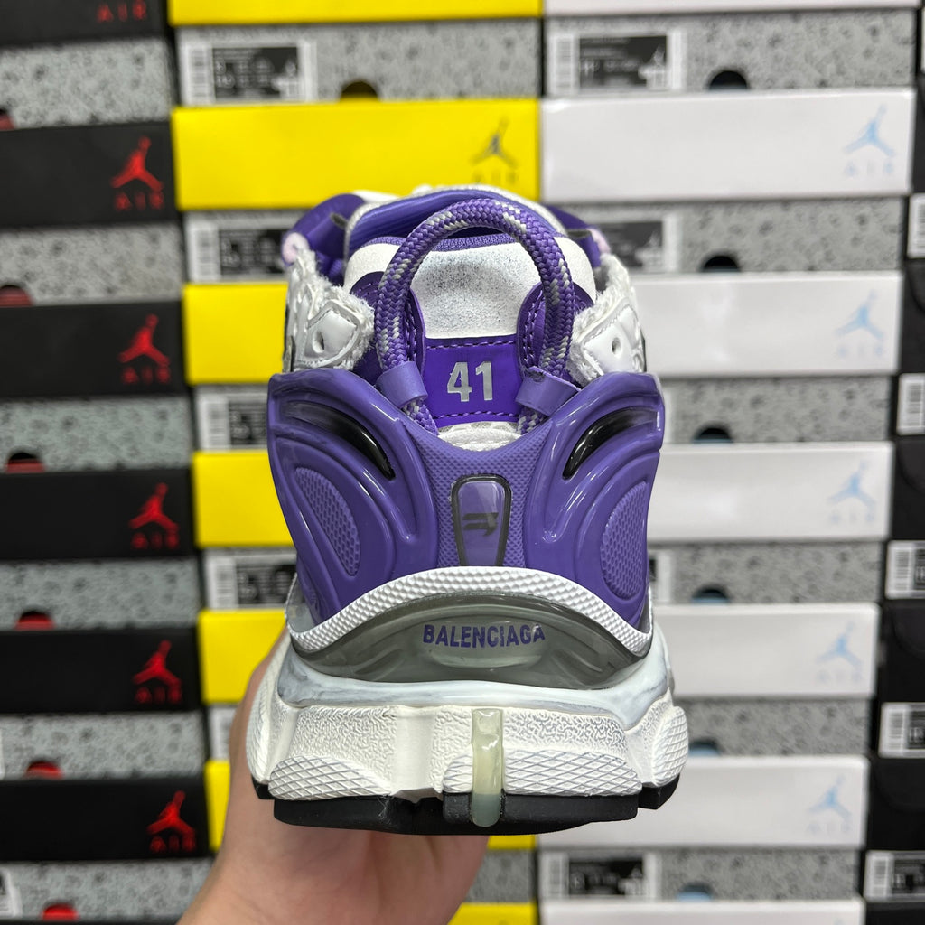 Back view of white and purple sneaker with purple heel cage and logo.