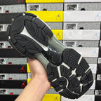 Black rubber outsole of white and purple sneaker with tread pattern.