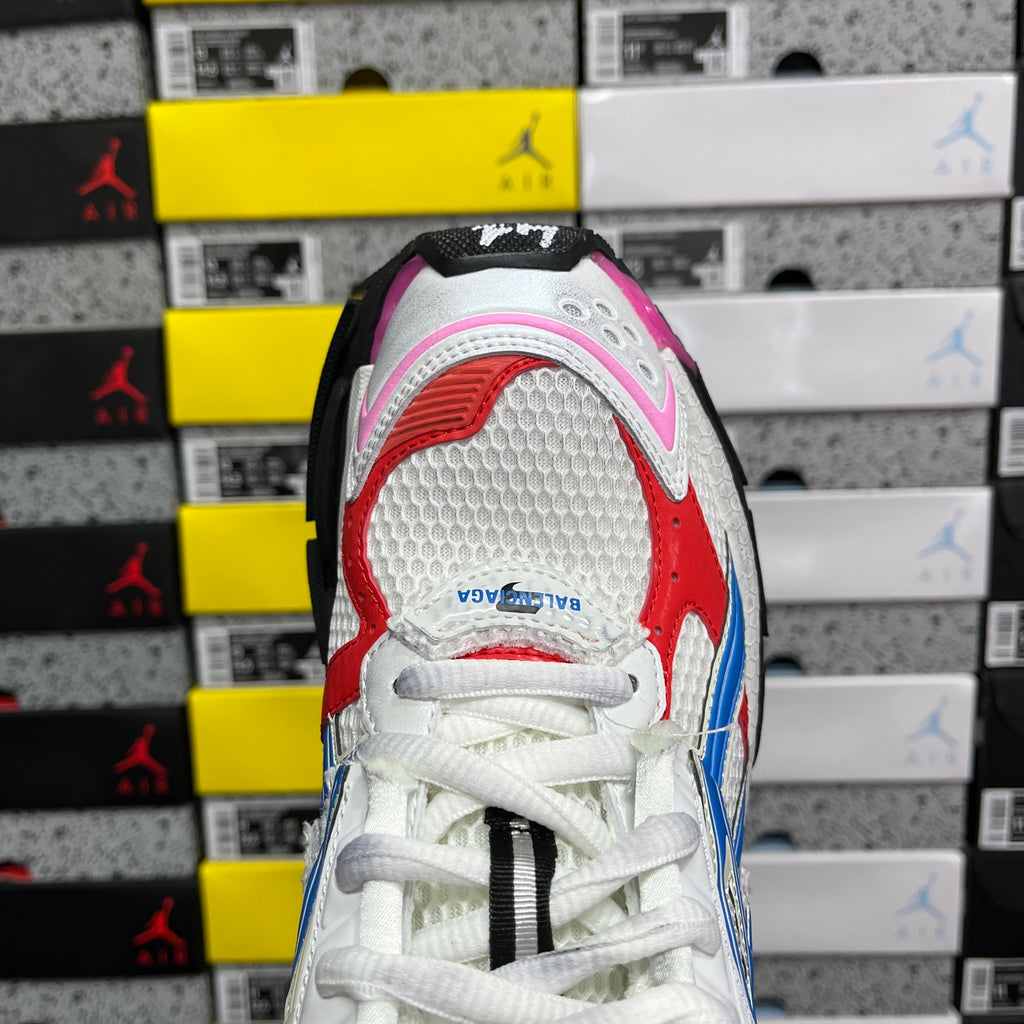 Unisex sneaker heel close-up with white upper, red and blue stripes, pink toe trim