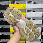 Sneaker outsole view with tan tread pattern and pink edge trim