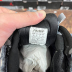 Inside label on black-and-grey lace-up sneaker, size chart and sizing numbers.