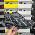 Grey and black lace-up runner sneakers with mesh panels and logo detailing.