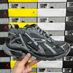 Grey and black lace-up runner sneakers with mesh panels and logo detailing.