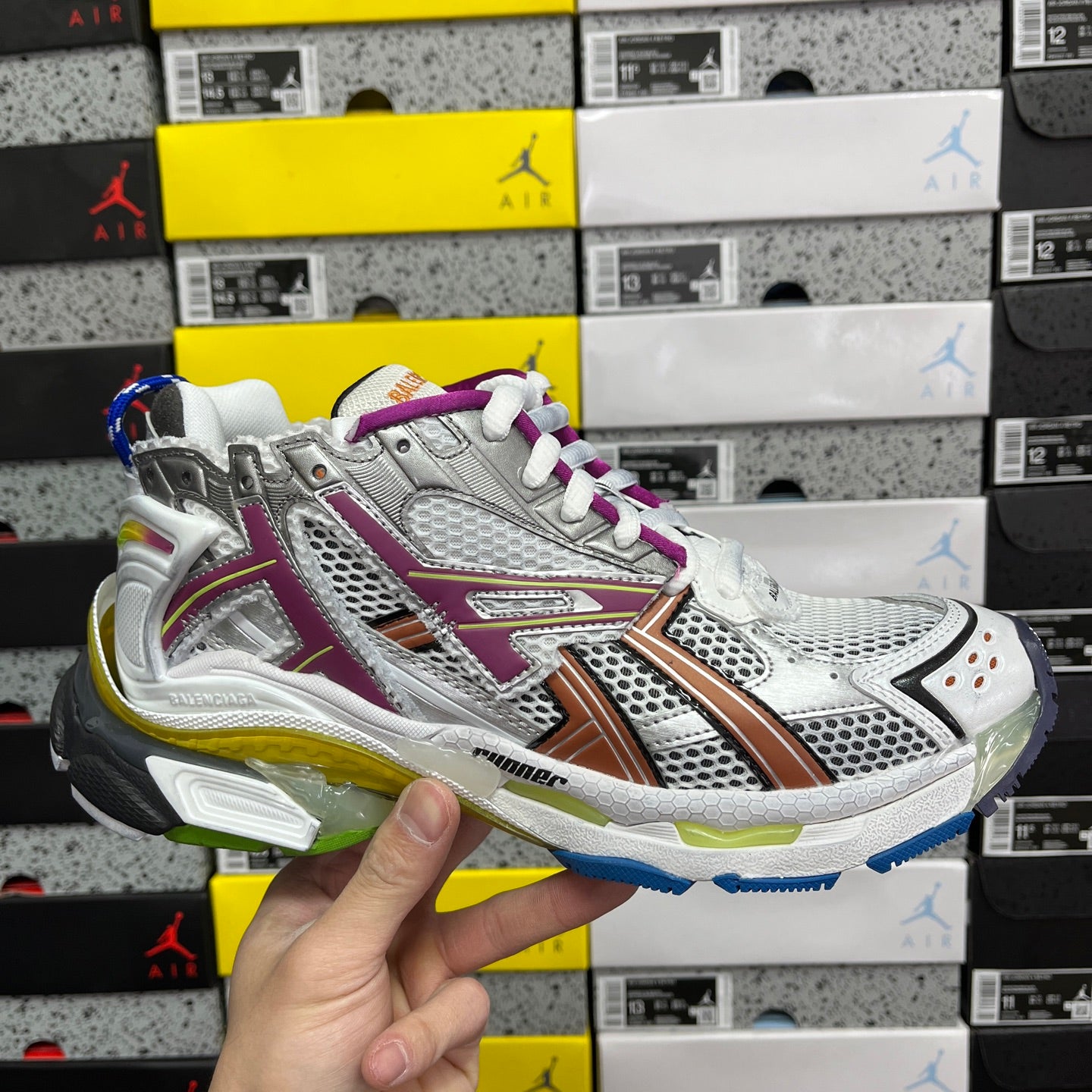 Silver multi-panel sneaker with purple and orange stripe, white laces and blue sole