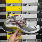 Silver multi-panel sneaker with purple laces, orange stripe, and blue outsole trim