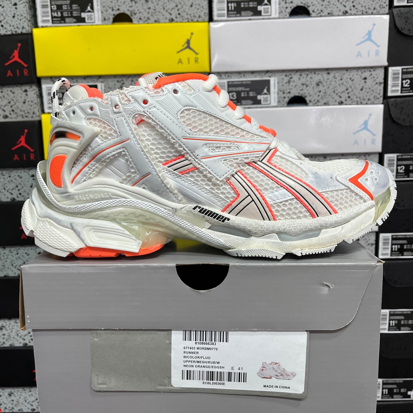 Balenciaga runner sneakers side view, white upper with orange accents and textured sole