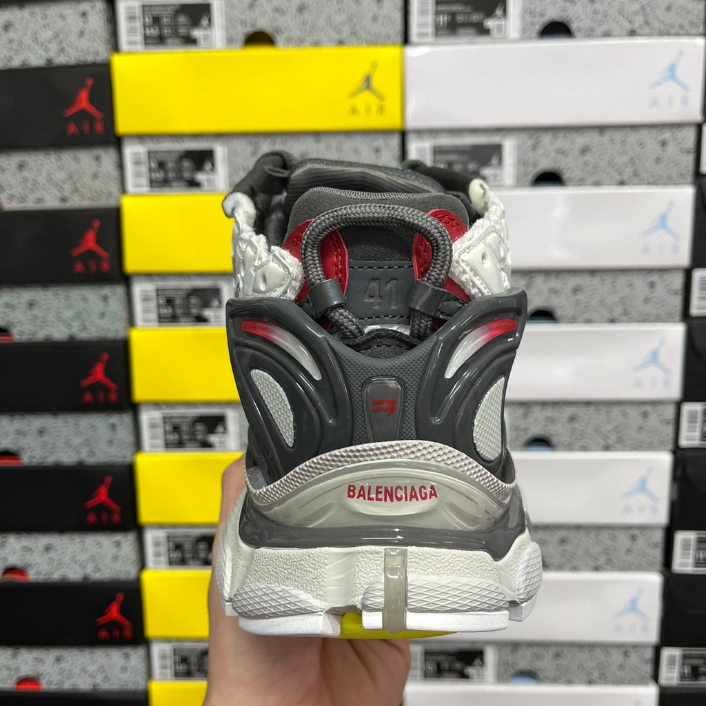 Back view of gray and white sneaker with BALENCIAGA heel badge and black strap