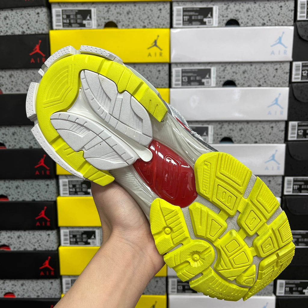 Lime yellow and white sneaker outsole with tread pattern and red midfoot insert