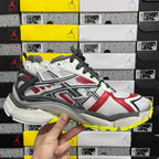 White, red, and black low-top sneaker with black laces and yellow outsole edge
