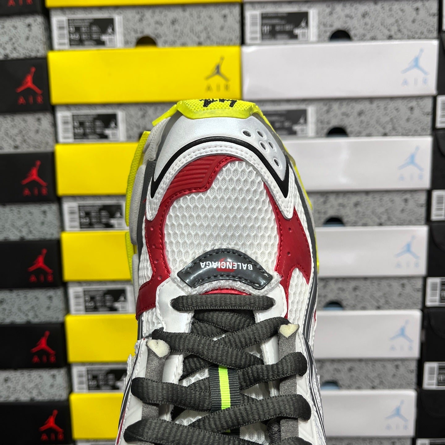 White sneaker toe with red panels, black laces, and perforated upper detail