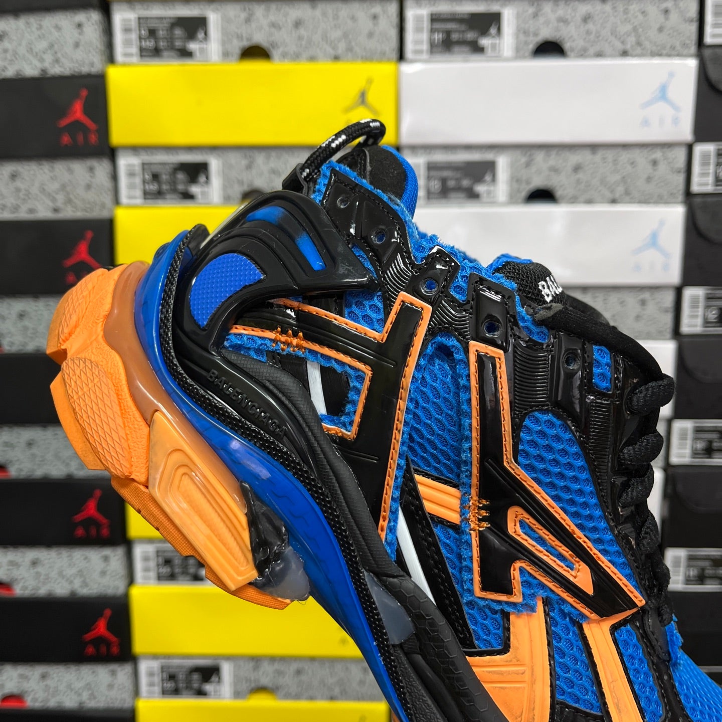 High-top unisex sneakers angled view: blue mesh, orange accents, black lace-up