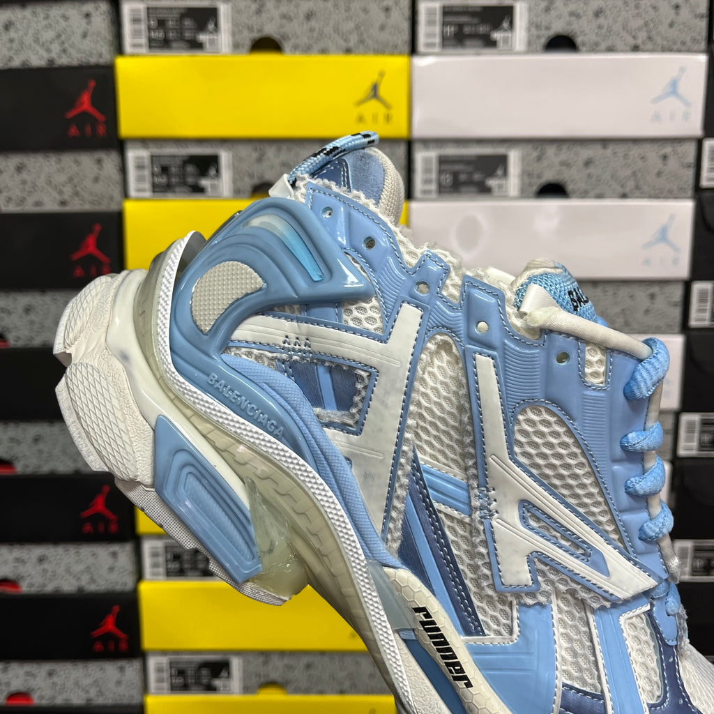 Blue and white athletic sneaker, angled side view with molded outsole