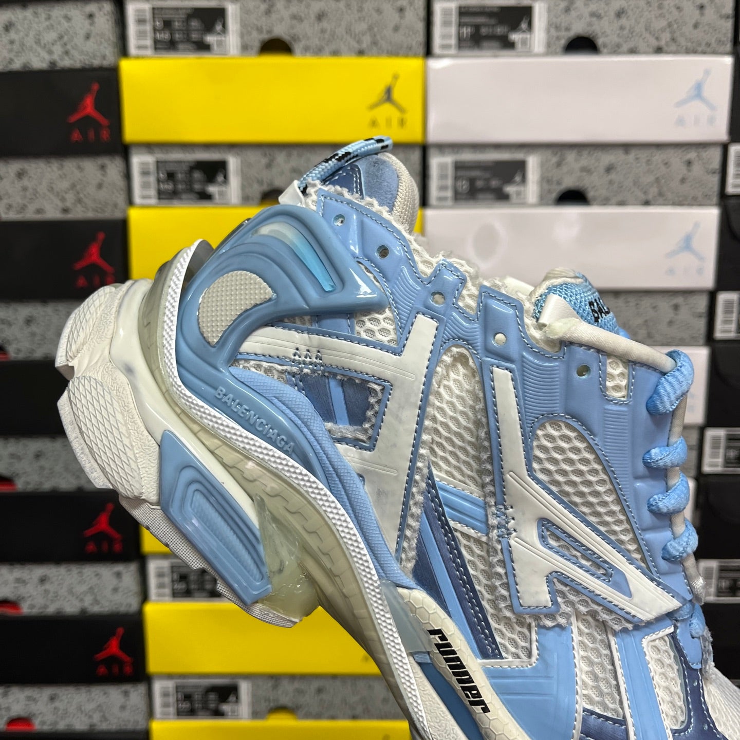 Blue and white athletic sneaker, angled side view with molded outsole